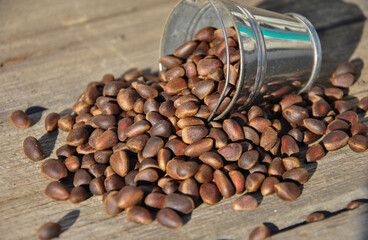 Unshelled pine nuts on and a small bucket on a wooden table. pine cone kernels