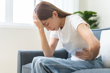 Sick asian young woman in pain, hand holding belly, stomach pain from food poisoning, girl hurt abdomen ache and digestive problem, gastritis or diarrhea. Health care inflammation, abdominal problem