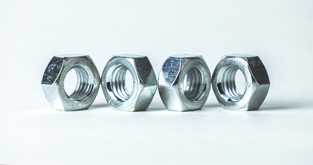 Metallic nuts arranged in a row on a light background