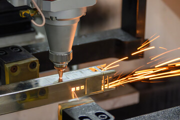 Close up scene the fiber laser cutting machine cut the square shape stainless steel tube with sparkling light.