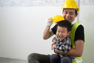 Joyful Asian man father hug and roleplay as engineer or worker with happy little child son at home. Full length carefree two generations family having fun, practicing learning playing in pair together