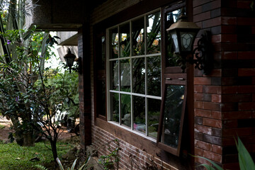 white framed window and vintage lantern. Lush green garden. 