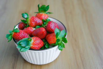 Fresh Organic Ripe Strawberries In A Porcelain Bowl over wooden background