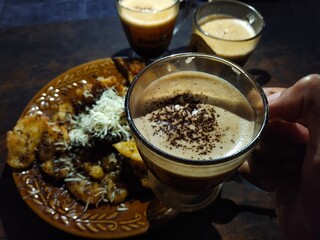 Close-up of coffee and crispy fried bananas topped with cheese. Delicious snack time.