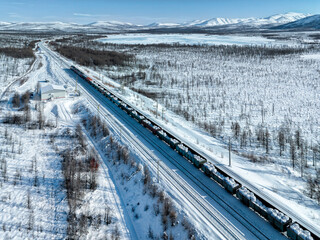 Train with wagons against the backdrop of snowy mountains. Cargo transportation industry