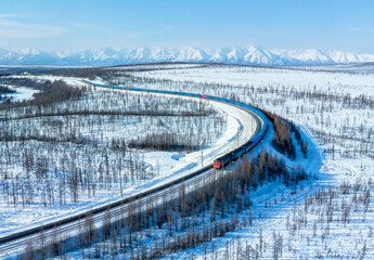 Train with wagons against the backdrop of snowy mountains. Cargo transportation industry