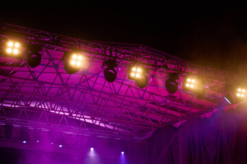 Close-up view of professional stage lighting mounted on metal truss. Bright spotlights at concert...