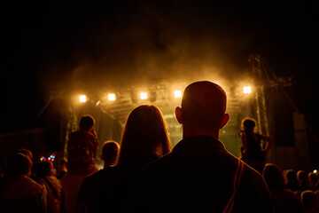 Vibrant live concert scene with band performing on stage under bright spotlights. Couple enjoying...