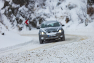 Blurry car on the snowy mountain road during severe conditions