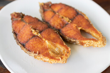 Deep fried sea bass with fish sauce in white plate.
