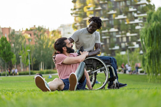 Friends with prosthetic leg and wheelchair support each other. Diversity and human connection bonding in urban park
