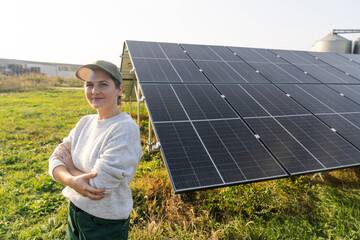 Female farmer on a modern farm using solar panels. Agricultural silos in the background..