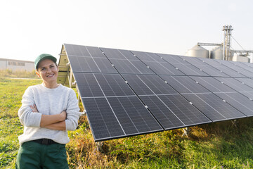 Female farmer on a modern farm using solar panels. Agricultural silos in the background..