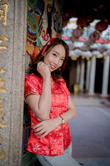 A woman in a red Chinese dress poses for a photo. She is smiling and she is happy