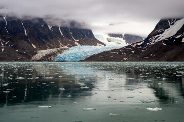 The coast of Spitsbergen, a glacier flows from a mountain gorge into the Arctic Ocean