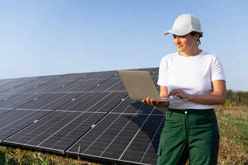 Female farmer with laptop on a modern farm using solar panels