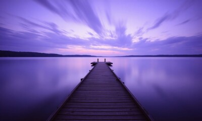 Obraz premium Long wooden dock stretching into calm purple lake.