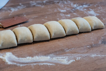 A rolled yeast dough is cut into slices for making cinnamon rolls