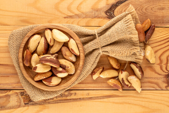 Brazil nuts without shells in a jute bag on a wooden table, close-up, top view.