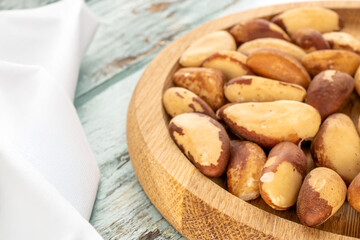 Generated Image. Brazil nuts without shells on a wooden plate on a wooden table, close-up.