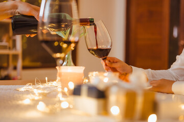 party, romance, valentine, couple, romantic, anniversary, celebrate, affection, celebrating, luxury. A person is pouring wine into a glass while another person is holding a wine glass.
