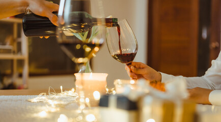valentine, romance, couple, dining, celebrating, celebrate, affection, party, diner, wine. A person is pouring wine into a glass while another person is holding a wine glass.