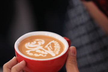 Milk pours into cup creating coffee art by barista.