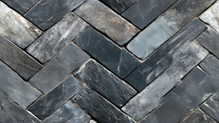 Textured slate tiles arranged in herringbone pattern, showcasing mix of charcoal and gray tones. This design adds modern touch to any space