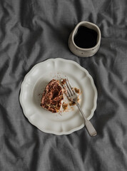 A cup of coffee and a portion of tiramisu on a gray background, top view
