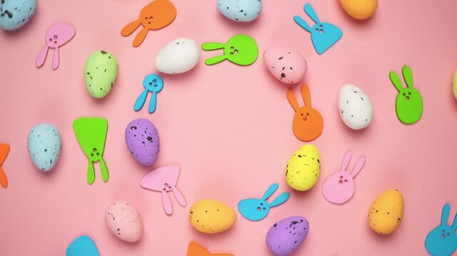 Top view of Easter decor, marble multi-colored eggs and bunny on pastel pink background. Easter party concept, 360 degrees rotation, flat lay copy space
