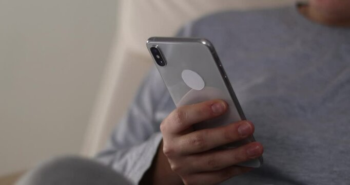 woman's hands scroll mobile phone keypad to check messages at home in evening
