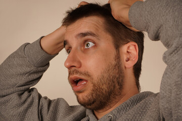 Obraz premium Holding his hair in his fist, the man shows clear signs of tension or stress. His face reflects a moment of suffering. The pose creates an irresistible feeling of mental tension.