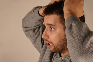 Obraz premium Holding his hair in his fist, the man shows clear signs of tension or stress. His face reflects a moment of suffering. The pose creates an irresistible feeling of mental tension.