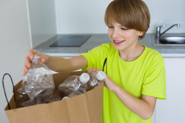 Smiling cute boy recycling plastic bottles