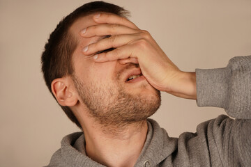 Fototapeta premium With his hand pressed against his face, the man shows a facepalm, indicating a moment of embarrassment or frustration. This gesture communicates a feeling of being overwhelmed by the situation.