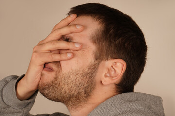 Fototapeta premium The man places his palm on his face, performing a facepalm gesture. This classic gesture expresses frustration, disbelief, or embarrassment. It s a universal sign of exasperation or regret.