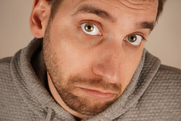 In a close-up shot, a young man s wrinkled forehead expresses his surprise. The furrows on his brow reflect his immediate reaction to something unexpected. His face conveys shock and disbelief.
