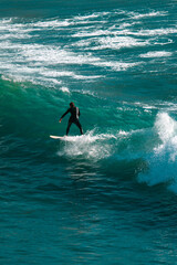 Surfing big waves on a blue sea
