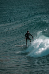 Surfing big waves on a blue sea