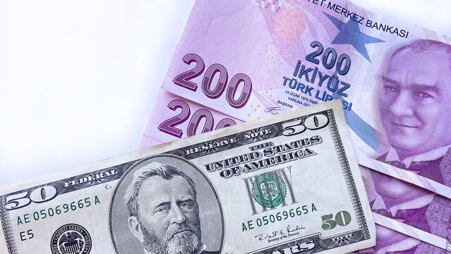 A comparison of currency featuring an old-design 50 US dollar bill placed on top of several 200 Turkish lira banknotes, arranged on a white background, emphasizing international exchange and finance.