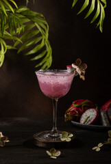 Refreshing pitaya cocktail garnished with tropical flower and ice cubes