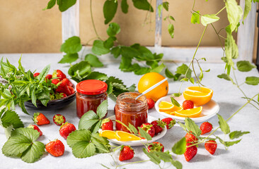 Homemade strawberry jam with fresh strawberries, orange slices and mint leaves