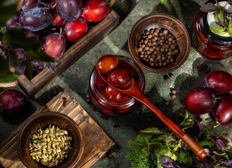 Pickled plums in syrup are served with spices and herbs