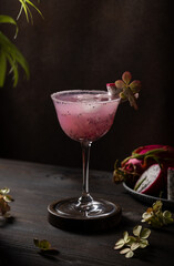 Refreshing dragon fruit cocktail garnished with exotic flower and ice cubes