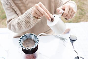 Asian woman making a handcraft drip coffee at the camping ground.