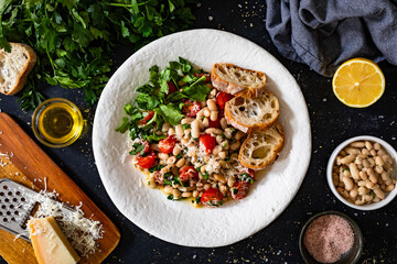 White beans with cherry tomatoes, parmesan, lemon and garlic on black table
