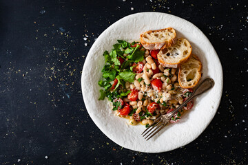 White beans with cherry tomatoes, parmesan, lemon and garlic on black table