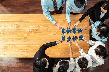 Multiethnic business people holding jigsaw pieces and merge them together as effective solution...