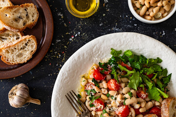 White beans with cherry tomatoes, parmesan, lemon and garlic on black table