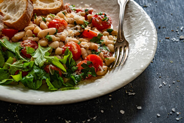 White beans with cherry tomatoes, parmesan, lemon and garlic on black table